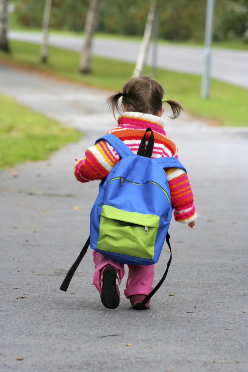 Child wearing a backpack walking to school
