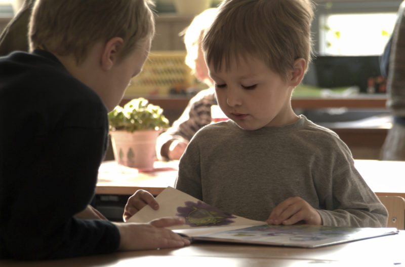 2 children reading a book at a table