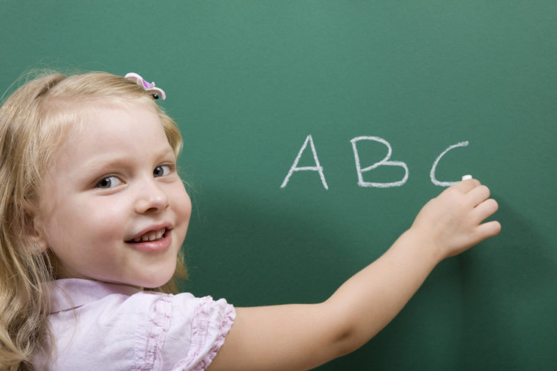 Child writing ABC on a chalkboard